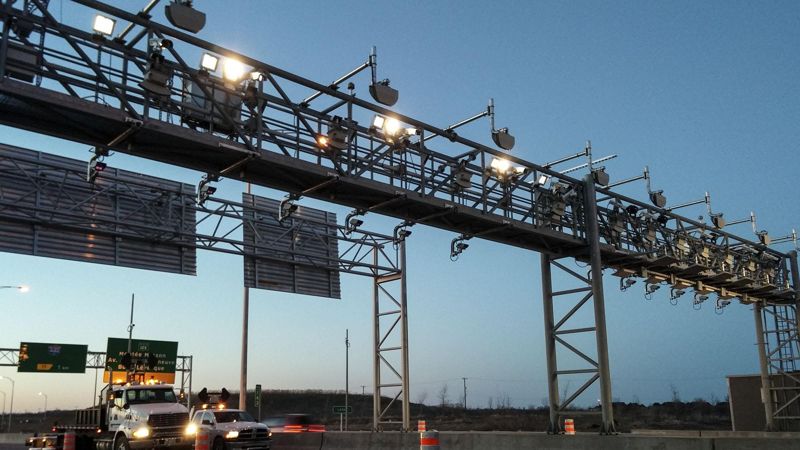 A toll gantry with cameras over a highway at dusk