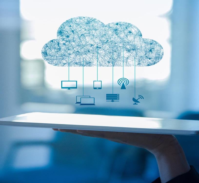 A hand holding a tablet with a cloud above it connected to screens, servers and antennas